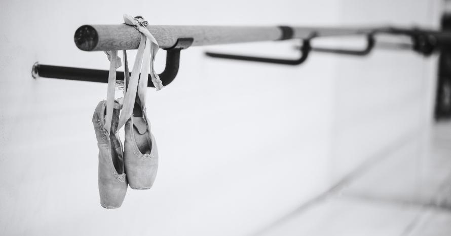 Ballet shoes hanging on wooden barre